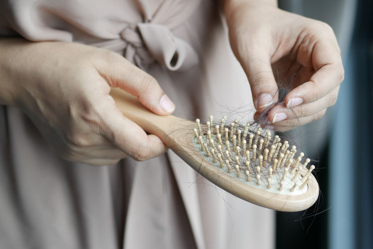 Femme retirant les cheveux emmêlés d'une brosse pour un nettoyage régulier et hygiénique