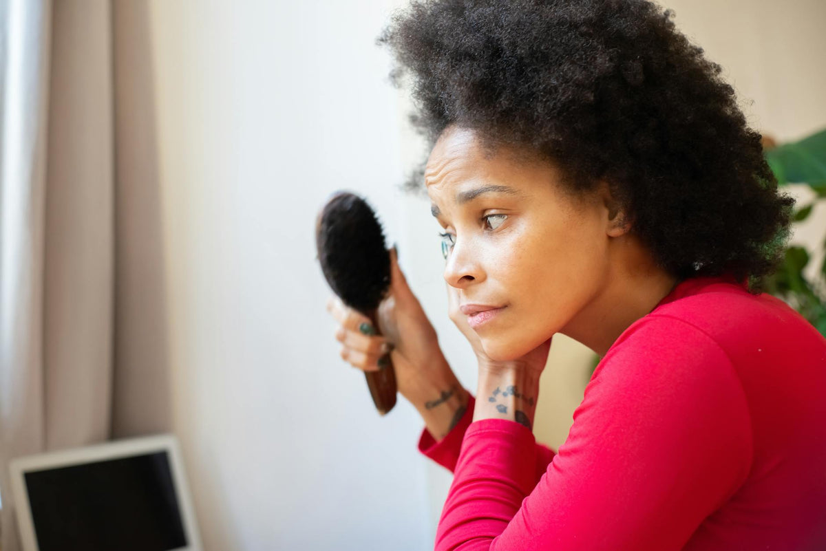 Femme se brossant les cheveux — massage du cuir chevelu pour stimuler la pousse capillaire