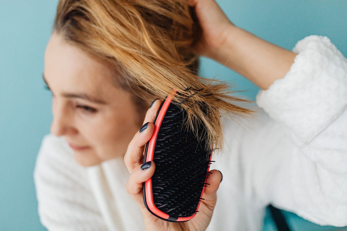 Femme brossant ses cheveux blonds — guide pour garder un blond lumineux sans reflets jaunes
